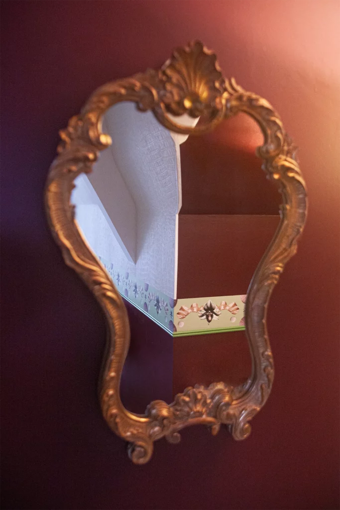 Gros plan de frise murale en collage, textures papier et motifs organiques. Détail dans le miroir.